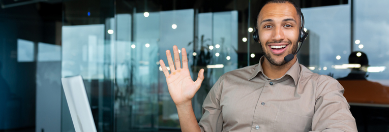 A person wearing headphones and waving their right hand at the camera.